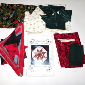 May include: A quilting kit for a Feathered Star Christmas Tree Skirt. The kit includes fabric pieces in red, green, black, and white with a variety of patterns. The kit also includes a pattern guide with instructions for making the quilt.