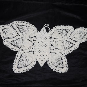May include: White crocheted butterfly doily with a delicate lace pattern.