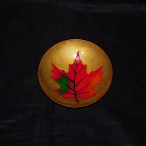 May include: A gold bowl with a red, green and orange maple leaf painted on the inside.
