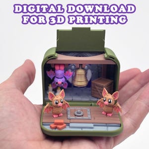 May include: A miniature 3D printed diorama featuring a green exterior shell, two small brown bats with pink ears and wings, one purple bat hanging from the ceiling, a gold bell, a wooden crate, and candles. Text reads: DIGITAL DOWNLOAD FOR 3D PRINTING.