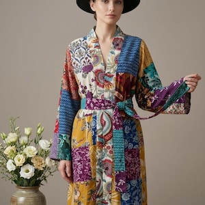 May include: A patchwork robe with a vibrant mix of colors and patterns, including floral and geometric designs. The robe features a matching belt and is paired with a black hat. The robe's design is a mix of blue, yellow, purple, and red.