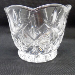 May include: A clear glass bowl with a cut glass design. The bowl has a scalloped rim and a pedestal base.