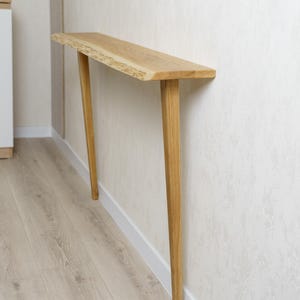 Konsola z naturalnym drewnem i krawędzią, dębowy stojak w korytarzu, meble w stylu mid-century modern, osłona grzejnika