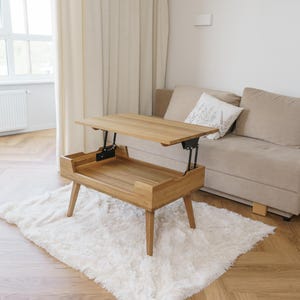 May include: A light brown wooden coffee table with a lift-top mechanism that elevates the surface. The table features four tapered legs and an open storage compartment beneath the raised top, showcasing a natural wood grain finish throughout.
