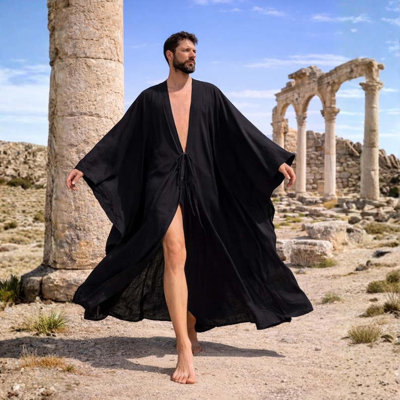 May include: A flowing, black robe with wide sleeves and a tie closure at the waist. The robe is worn outdoors against a backdrop of ancient ruins and a blue sky. The fabric appears lightweight and airy.