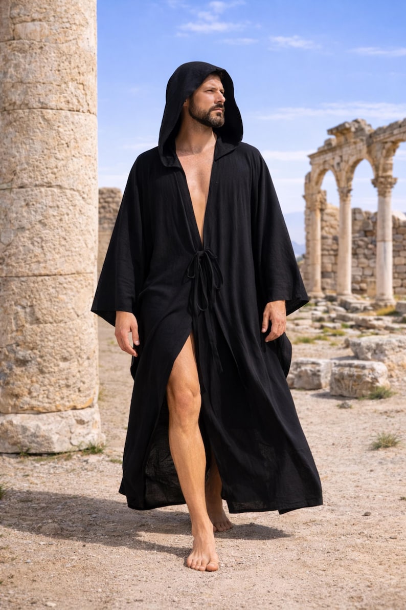 May include: A black hooded robe with a tie closure, worn open, with long sleeves. The robe is made of a flowing fabric. The background features ancient ruins and a blue sky. The robe is suitable for cosplay or casual wear.