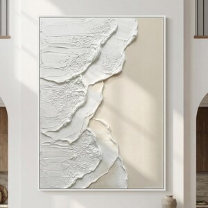Può includere: Dipinto astratto incorniciato con un design a onde bianche strutturate su sfondo beige. L'opera d'arte è racchiusa in una cornice bianca, creando un'estetica moderna e minimalista. Il dipinto evoca un senso di calma e serenità.