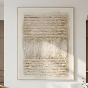 May include: A rectangular wall art piece featuring a beige and cream textured surface. The composition consists of three horizontal sections: a top and bottom area with horizontal ridges and a central band with vertical raised lines.