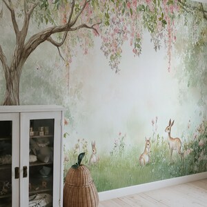 May include: A mural depicting a forest scene with a large tree, pink flowers, and rabbits. A white cabinet and a woven basket are in the foreground. The room has light wood flooring.