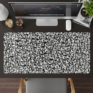 May include: Rectangular desk mat with a black and white skull pattern. The mat is designed to cover a desk surface. The skulls are intricately drawn, creating a striking and alternative design.