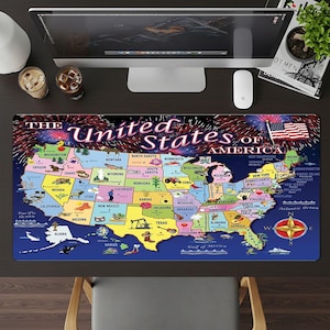 May include: A colorful desk mat featuring a map of the United States with each state labeled. The mat includes the text "The United States of America" and a depiction of fireworks and the American flag. The mat is rectangular.