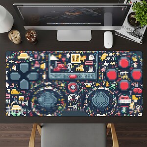 May include: A large, rectangular desk mat with a pixelated video game controller design. The mat is mainly dark blue with colourful pixel art elements, including buttons, joysticks, and a screen. The design is reminiscent of retro gaming aesthetics.