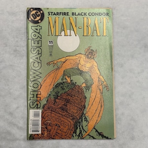 May include: A vintage comic book titled Showcase 94 number 11 featuring Man-Bat on the cover. The illustration shows a yellow, bat-like creature with large wings perched atop a brown, carved stone structure against a pale green background.