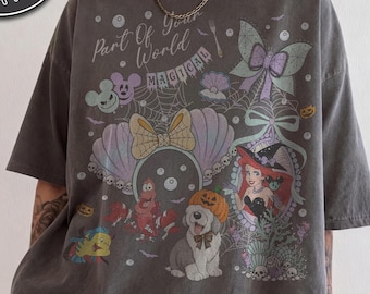Op de afbeelding: Een antracietgrijs t-shirt met korte mouwen en een grafische print met de tekst Part Of World MAGICAL. Het ontwerp bevat een zeemeermin, een krab, een hond met een pompoen, een vlinder, spinnenwebben en schelpmotieven in gedempte pasteltinten.