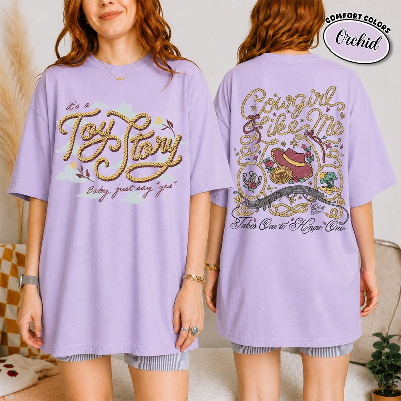 K&ouml;nnte beinhalten: Ein orchideenfarbenes T-Shirt mit einer Grafik auf der Vorderseite, die den Text "it's a Toy Story Baby, just say 'yes'" in seilartiger Schrift zeigt. Die R&uuml;ckseite zeigt eine detaillierte Illustration eines Cowboyhutes, eines Seils und des Textes "Cowgirl like Me".