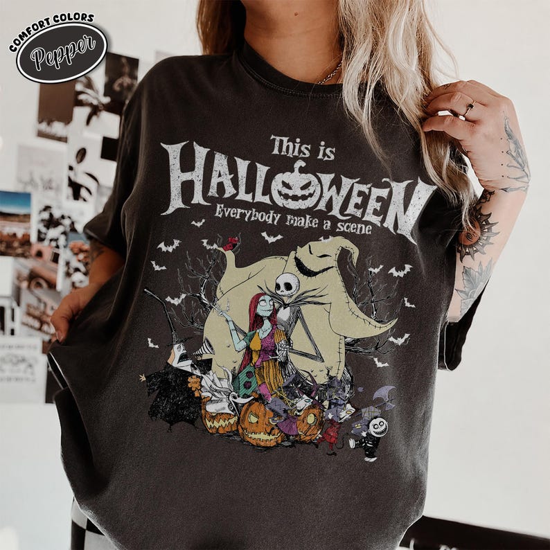 May include: Dark gray t-shirt featuring a graphic from "The Nightmare Before Christmas." The design includes Jack Skellington, Sally, and Oogie Boogie, with the text "This is Halloween" and "Everybody make a scene."