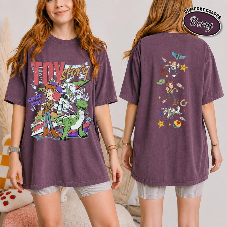 K&ouml;nnte beinhalten: Ein beerenfarbenes Kurzarm-T-Shirt mit Toy Story-Grafiken. Die Vorderseite zeigt Woody, Buzz Lightyear und Rex mit dem Text Toy Story Since 1995. Die R&uuml;ckseite zeigt eine vertikale Anordnung von Charakteren, darunter Woody und Buzz.
