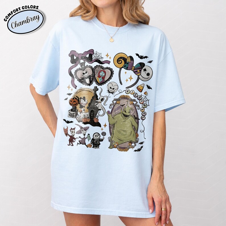May include: A light blue t-shirt featuring a graphic print of characters and motifs from The Nightmare Before Christmas, including Jack Skellington, Sally, Oogie Boogie, Zero, and various holiday-themed icons like pumpkins and spiderwebs.