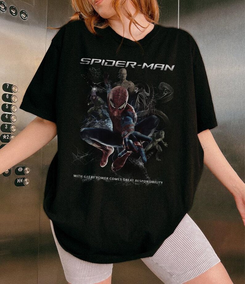 May include: Black Spider-Man t-shirt with a graphic of the superhero and the text "SPIDER-MAN" above and "WITH GREAT POWER COMES GREAT RESPONSIBILITY" below. The t-shirt has a crew neck and is a classic fit.