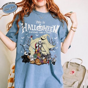 Puede incluir: Camiseta azul claro con el texto "This is Halloween" y un gr&aacute;fico con personajes de Pesadilla antes de Navidad. El dise&ntilde;o incluye a Jack Skellington, Sally y otros elementos tem&aacute;ticos de Halloween.