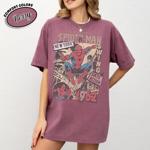 Puede incluir: Camiseta color bayas con un gr&aacute;fico vintage de Spider-Man. El dise&ntilde;o incluye el texto "THE AMAZING SPIDER-MAN", "NEW YORK" y "1962". La camiseta es de color confort y tiene un corte relajado.