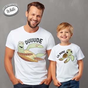 May include: White t-shirts with turtle graphics. One shirt says "DUUUDE" with a turtle illustration, and the other says "LIL DUDE" with a matching turtle. The shirts are Comfort Colors.
