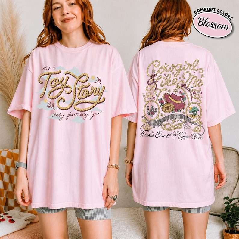 K&ouml;nnte beinhalten: Ein hellrosa T-Shirt mit einem Frontaufdruck, der den Text "it's a Toy Story Baby, just say "yes"" in seilartiger Schrift zeigt. Die R&uuml;ckseite zeigt ein Western-Motiv mit dem Text "Cowgirl like Me" und "Takes One to Know One".