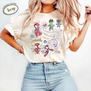 以下が含まれることがあります： スパイダーマン、ハルク、ブラックパンサー、スパイダーグウェンの漫画イラストが描かれたアイボリー色のTシャツ。「Spidey and His Amazing Friends 2023」の文字も含まれています。柔らかい素材で作られたTシャツです。