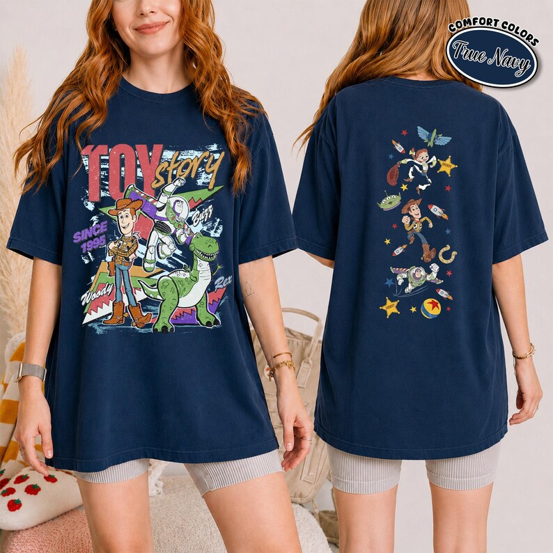 K&ouml;nnte beinhalten: Ein marineblaues T-Shirt mit Toy Story-Figuren. Die Vorderseite zeigt Woody, Buzz Lightyear und Rex mit dem Text "TOY story SINCE 1995". Die R&uuml;ckseite zeigt eine vertikale Anordnung verschiedener Figuren und Symbole, darunter Sterne und Raketen.