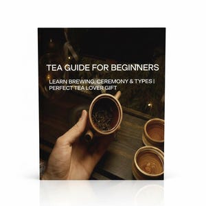 Puede incluir: Un libro titulado "TEA GUIDE FOR BEGINNERS" con el texto "LEARN BREWING, CEREMONY & TYPES | PERFECT TEA LOVER GIFT." La imagen muestra una mano sosteniendo una pequeña tetera marrón con hojas de té en su interior. También se ven dos pequeñas tazas de té de madera.