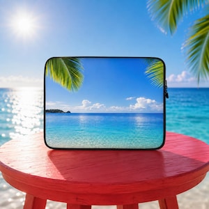 Könnte beinhalten: Eine rechteckige Laptoptasche mit einer lebendigen tropischen Strandszene, klarem blauem Wasser, einem hellen Himmel und grünen Palmwedeln. Die Tasche hat einen schwarzen Rand und einen Reißverschluss sowie einen hochauflösenden Druck einer Küstenlandschaft.