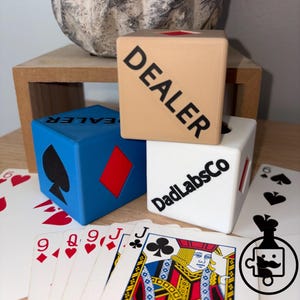 Puede incluir: Un letrero de madera hecho a mano con el texto "Bienvenido a nuestro hogar" en un estilo manuscrito. El letrero está pintado de blanco con un acabado envejecido y un borde negro. Un pequeño corazón decorativo está adjunto en la parte inferior.