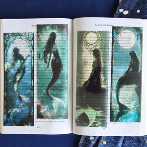 Peut inclure: Quatre marque-pages rectangulaires présentant des illustrations sombres et atmosphériques de sirènes dans des tons de bleu sarcelle, bleu et noir. Chaque marque-page affiche une silhouette de sirène unique sur un fond lunaire ou aquatique.