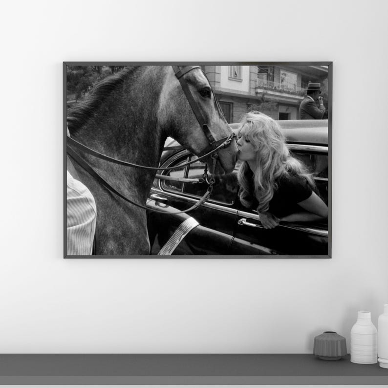 以下が含まれることがあります： 黒い持ち手と「But First, Coffee」のテキストが黒い太字で書かれた白いセラミックマグ。マグカップは白い表面に置かれています。