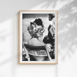 May include: Black and white framed print featuring a woman with blonde hair and sunglasses, seated in a director's chair. The chair back displays the name "BRIGITTE BARDOT" in bold letters. The image is a portrait, capturing a moment in time.