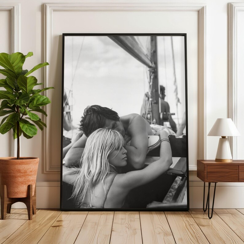 K&ouml;nnte beinhalten: Schwarz-Wei&szlig;-Druck in einem Rahmen, der ein sich umarmendes Paar auf einem Segelboot zeigt. Das Bild zeigt einen intimen Moment des Paares. Der Hintergrund zeigt das Takelwerk des Bootes und den Himmel.