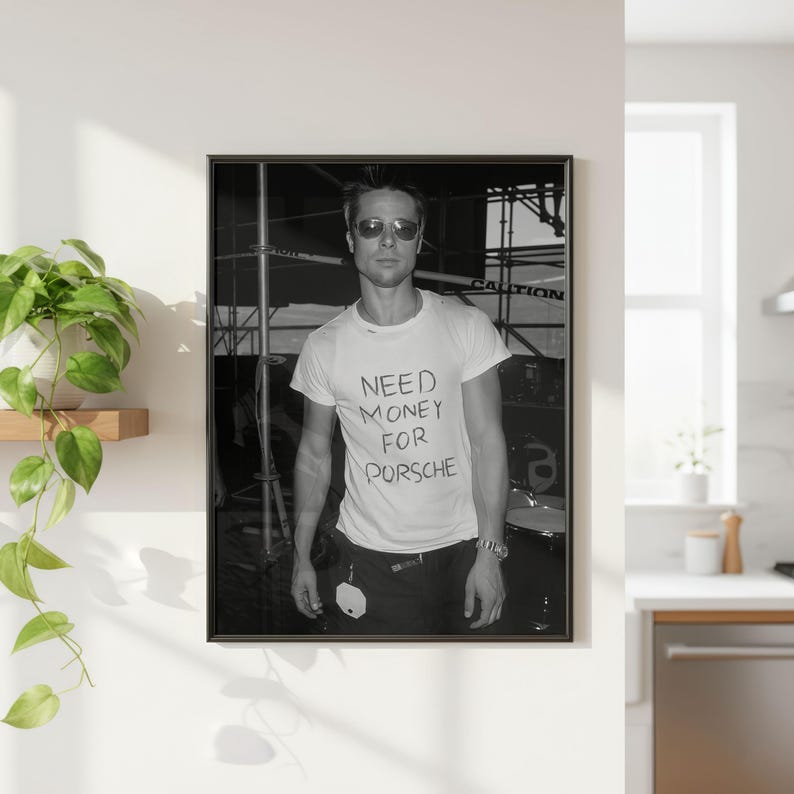 Puede incluir: Impresi&oacute;n enmarcada en blanco y negro que muestra a una persona con gafas de sol y una camiseta blanca con el texto "NEED MONEY FOR PORSCHE". La imagen es un retrato y se muestra en una pared blanca.