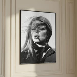 Puede incluir: Impresi&oacute;n enmarcada en blanco y negro de una mujer con cabello largo y una bufanda, fumando un cigarrillo. El retrato es un primer plano, que captura el rostro y la parte superior del cuerpo de la mujer. La imagen est&aacute; montada en un marco negro.