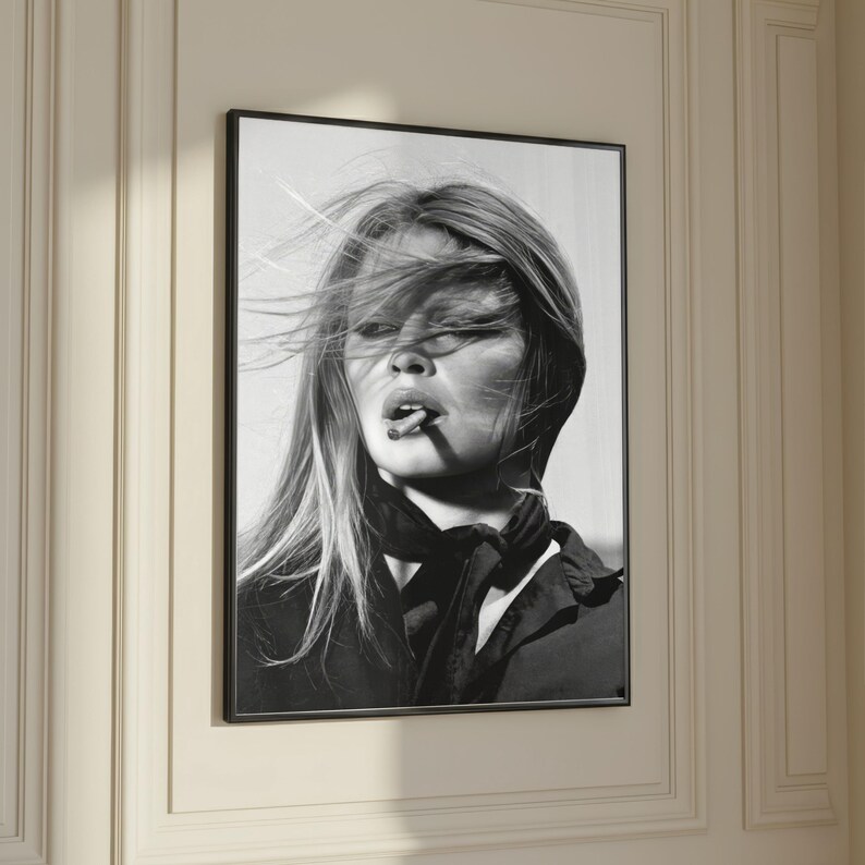 Puede incluir: Impresi&oacute;n enmarcada en blanco y negro de una mujer con cabello largo y una bufanda, fumando un cigarrillo. El retrato es un primer plano, que captura el rostro y la parte superior del cuerpo de la mujer. La imagen est&aacute; montada en un marco negro.