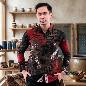 Może przedstawiać: Koszula z długim rękawem z wzorem batik. Koszula ma czerwono-czarną kolorystykę ze skomplikowanymi wzorami kwiatowymi i geometrycznymi. Rękawy i górna część koszuli są czerwone, a dolna część czarna.