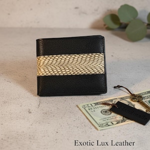Op de afbeelding: Zwart leren portemonnee met een beige slangenleer streep. Een twintig dollar biljet, sleutels en een "Handmade" label liggen naast de portemonnee. De tekst "Exotic Lux Leather" staat onderaan de afbeelding.