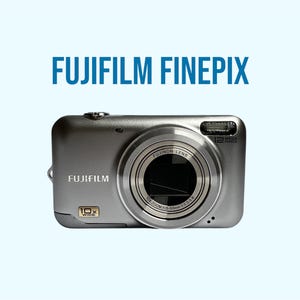Op de afbeelding: Een zilverkleurige Fujifilm FinePix digitale camera met een Fujinon-lens met 10x groothoekzoom. De voorkant van de camera toont het Fujifilm-logo, een 10x wide-embleem en een 12 megapixel-label. De tekst FUJIFILM FINEPIX staat boven de camera.