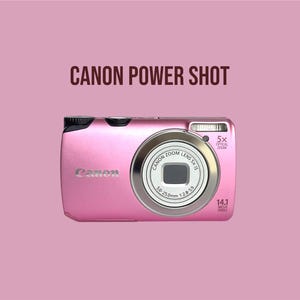Könnte beinhalten: Eine metallisch pinke Canon Power Shot Digitalkamera mit einem Canon Zoom Lens 5x IS 5.0-25.0mm 1:2.8-5.9, einem eingebauten Blitz und der Aufschrift 14.1 Mega Pixels. Das Kameragehäuse hat eine glatte Oberfläche mit schwarzen Akzenten.