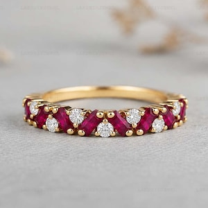 May include: A gold band ring featuring an alternating pattern of baguette-cut red rubies and round-cut white diamonds set in a prong setting. The ring displays a continuous design of gemstones around the visible portion of the metal band.