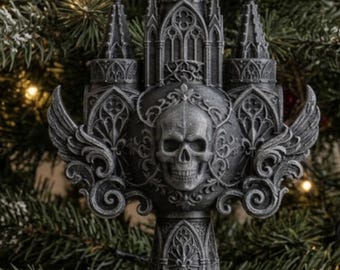 May include: A dark gray, three-dimensional ornament featuring a central human skull surrounded by intricate gothic architectural details, including pointed spires, arched windows, and ornate scrollwork with wing-like side extensions.