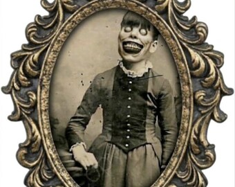 May include: An oval-shaped, ornate, antique-style gold frame containing a sepia-toned portrait of a person with a wide, toothy grin and large, pale eyes. The person wears a dark, button-up jacket with a high collar and ruffled cuffs.