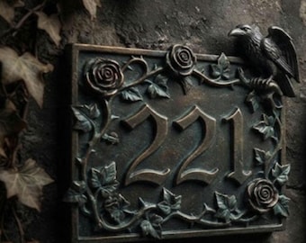 May include: A rectangular house number plaque displaying the digits 221 in a raised, metallic font. The plaque features a dark, weathered finish with sculpted relief details of climbing ivy vines, three blooming roses, and a perched raven.