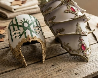 May include: A white helmet with green line patterns and gold filigree trim alongside a multi-layered white shoulder pauldron featuring gold filigree accents and embedded red oval gemstones. Both pieces display intricate metallic-style detailing.