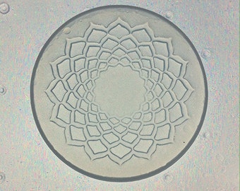 May include: A circular mandala design with a gray background and a white outline. The mandala is made up of a series of concentric circles and petals.