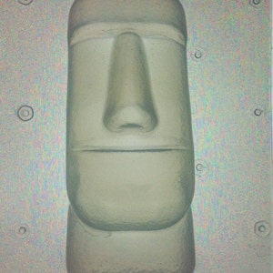 以下が含まれることがあります： 大きな鼻と平らな口をした人間の顔の白い石膏型。型は灰色の背景に置かれています。